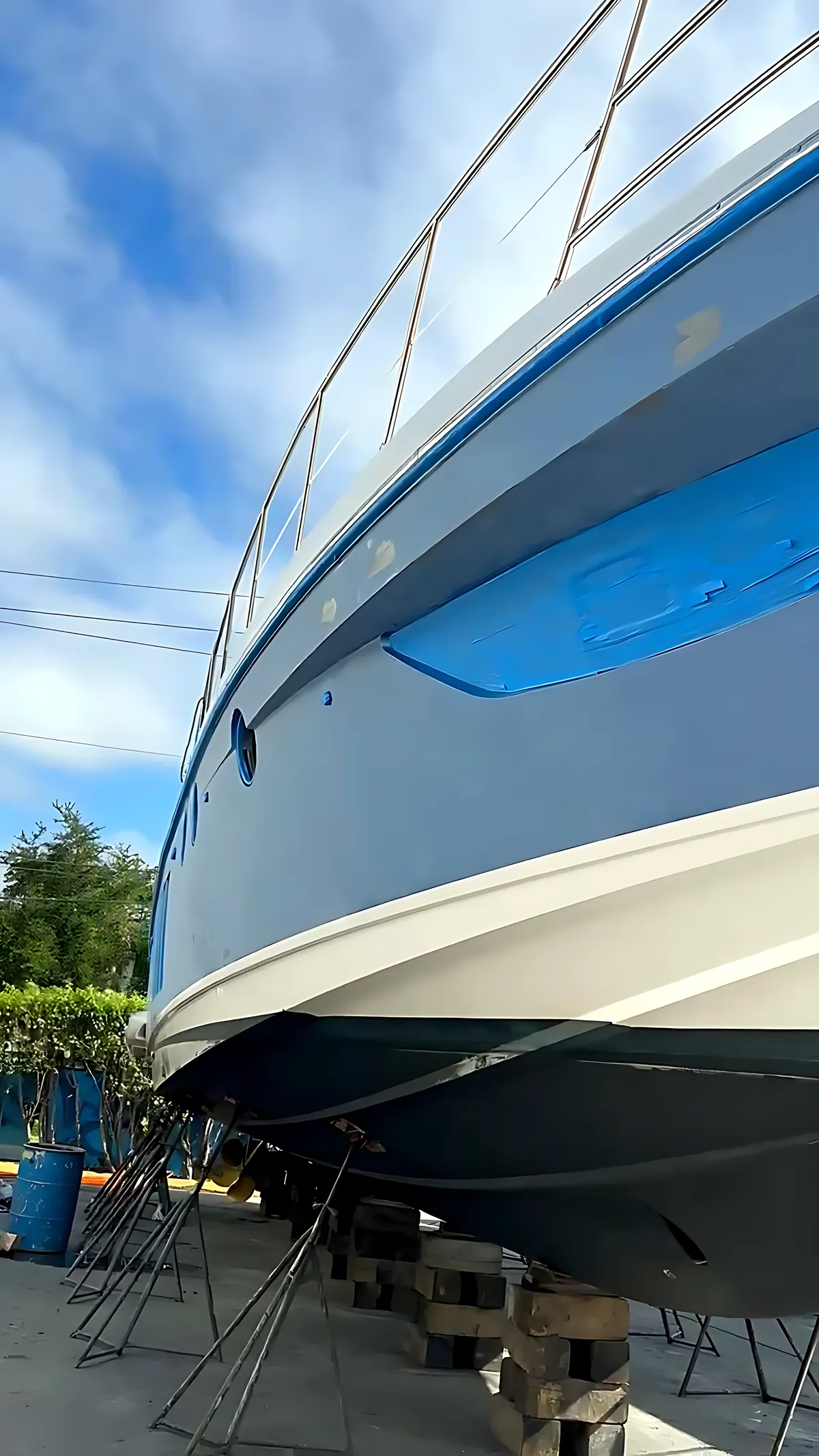 Blue-hulled motor yacht on jack stands in the boatyard
